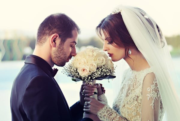 Na obrázku jsou novomanželé společně čichající ke svatební kytici