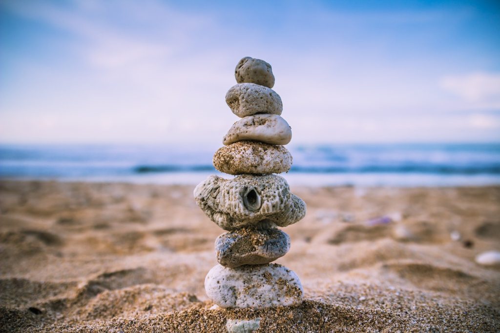 Na obrázku jsou na pláži do komínku vyrovnané kameny